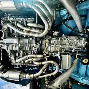Porsche 911 Targa underside with polished stainless-steel exhaust headers and detailed drivetrain components.